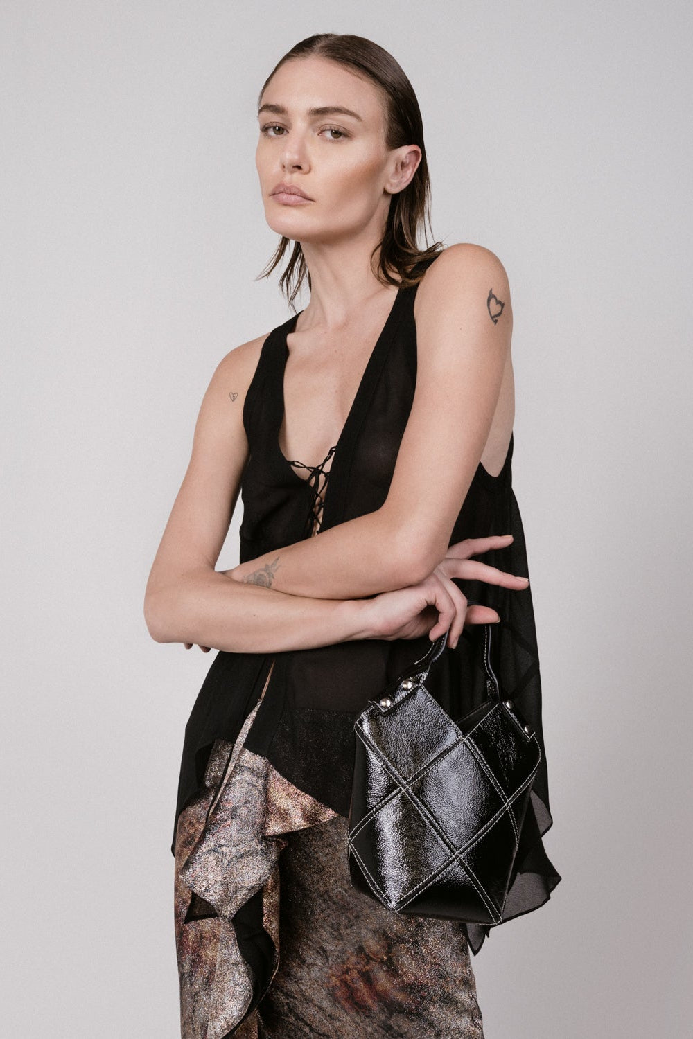 Woman holding a black handbag against a plain background