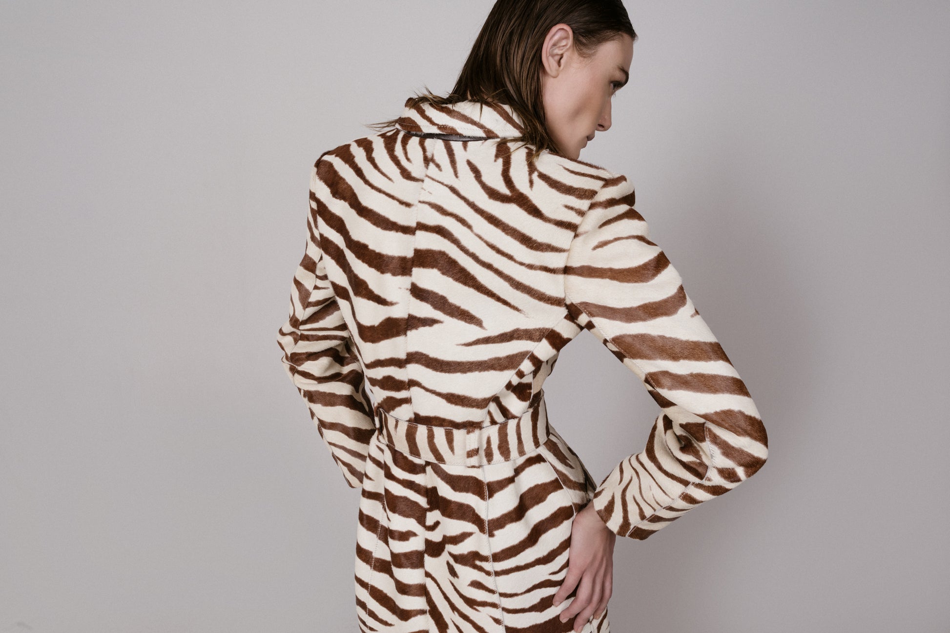 Person wearing a zebra print coat against a plain background