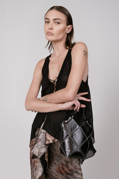 Woman holding a black handbag against a plain background