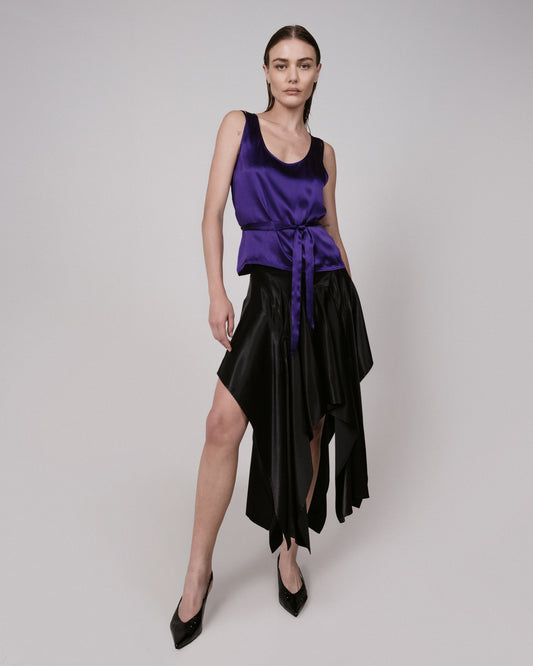 Woman wearing a purple top and black skirt on a plain background