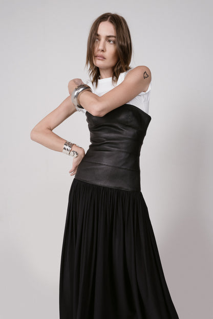 Woman wearing a black leather top and black skirt on a plain background